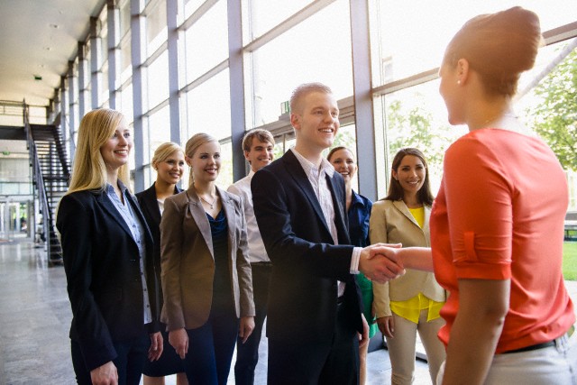 Team of business men and women greeting client in office --- Image by © suedhang/Image Source/Corbis